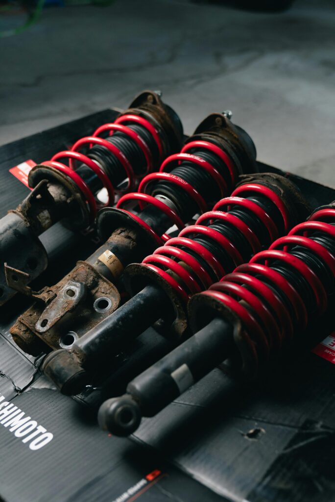 Close-up image of red coilover suspensions with a black background, ideal for automotive or mechanical themes.