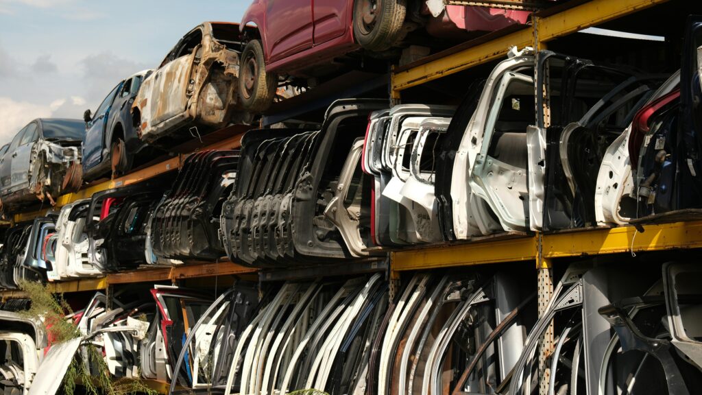 Rows of car doors stacked in a junkyard under a clear sky.
